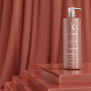 Kostume K.Fiber Repair shampoo bottle on a red platform with a red curtain background