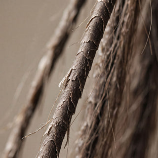 Close-up of dark brown hair extensions showing the textured, layered hair shafts and fine strands against a neutral beige background.
