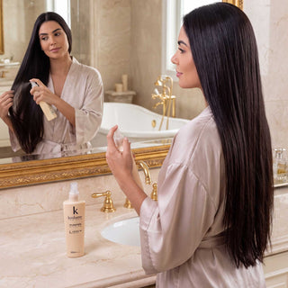 A woman applying Kostume Purifier Micellar Leave-in  Spray 12-in-1 to damp hair at home